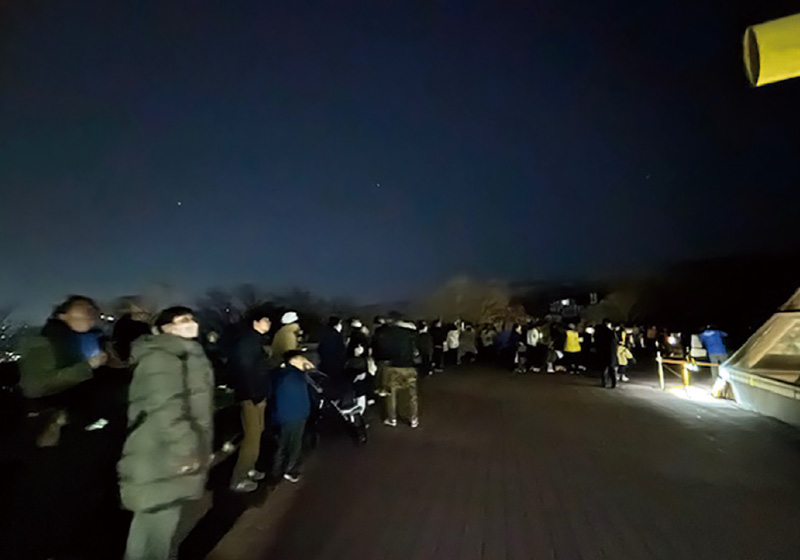 夜のデッキで星空観望会に参加する人々